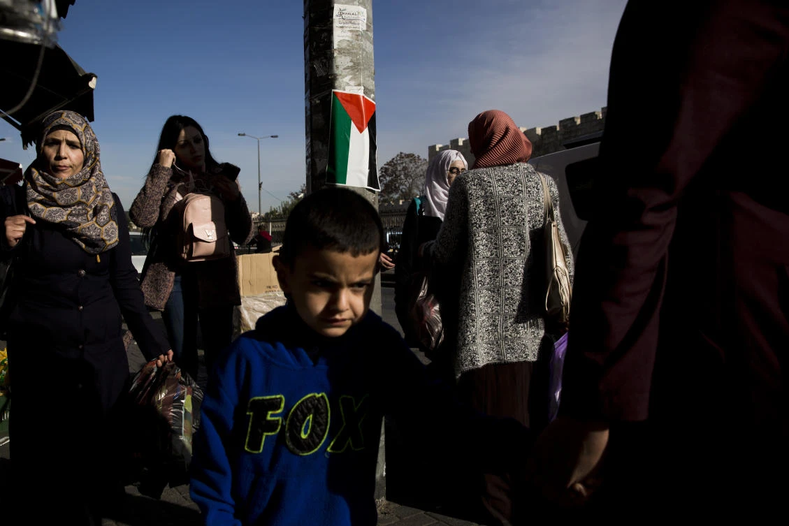 Above, Palestinians walk by a national flag in east Jerusalem. Palestinians make up 37 percent of Jerusalem’s population of 866,000, up from 26 percent in 1967 when Israel captured east Jerusalem. (AP)
