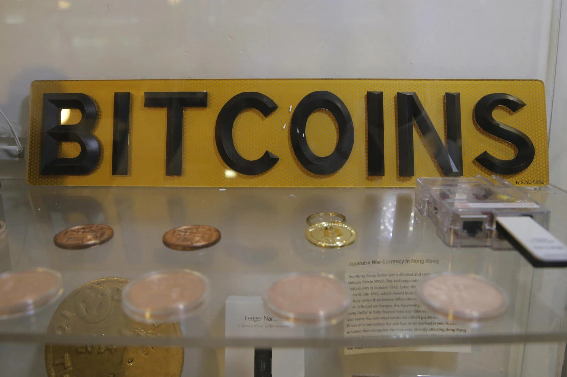 Zoobia Shahnaz is accused of fraudulently obtaining more than $85,000 through a bank loan and credit cards to buy bitcoin and other cryptocurrencies online. Above, coins and sign are displayed next to a Bitcoin ATM in Hong Kong. (AP)