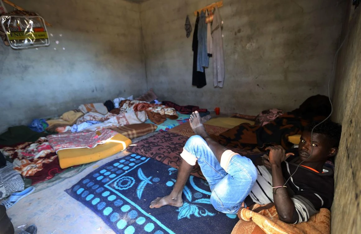 An African migrant looks toward the camera as he sits in a room at a Safe House in the town of Bani Walid, on the edge of the desert 170 kilometers (110 miles) southeast of the Libyan capital Tripoli on Dec. 12, 2017. For migrants who escape torture and starvation at the hands of people traffickers, a “Safe House” in an oasis town offers a rare commodity in Libya: shelter and medical care. (AFP/Mahmud Turkia)