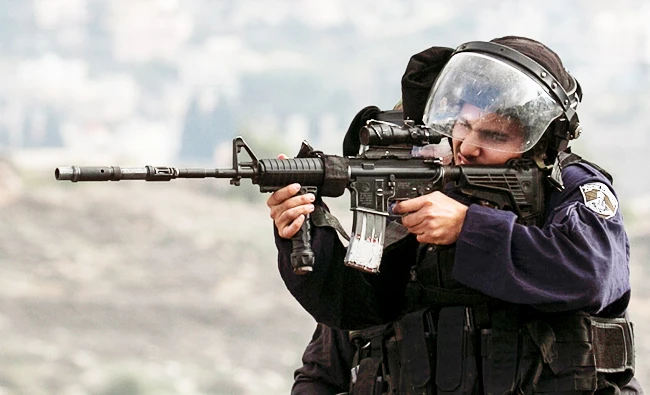 An Israeli border guard aims a rifle during clashes with Palestinian protesters near the Huwara checkpoint, south of Nablus. (AFP)