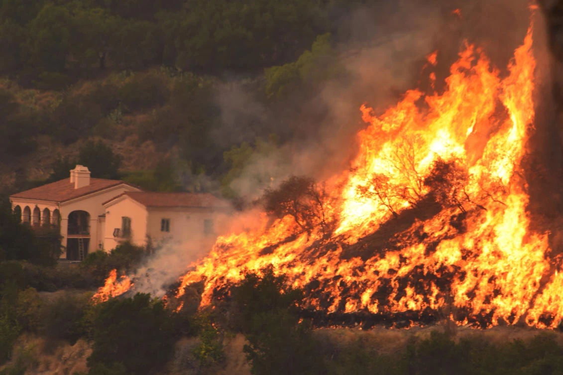 Flames from a backfiring operation rise behind a home in Santa Barbara. The so-called Thomas Fire, the fourth-largest in California history, continued to surge west, endangering thousands of homes, as forecasts called for a renewal of gusty winds. (AP)