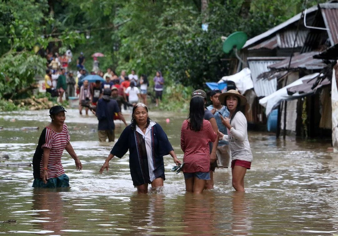 Villagers wade through a flooded street in Borongan, eastern Samar on Saturday. The state weather service said more heavy rain was expected in the coming hours with Kai-Tak forecast to slice across the rest of the central Philippines. (AFP)