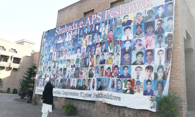 A man looks at a banner displaying pictures of the students who were killed during the APS massacre in Peshawar, Pakistan. (AN photo)