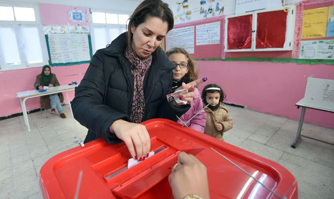 In this file photo, A Tunisian woman casts her vote with her children in the presidential elections on Dec. 21, 2014 at a polling station in the capital Tunis. (AFP)