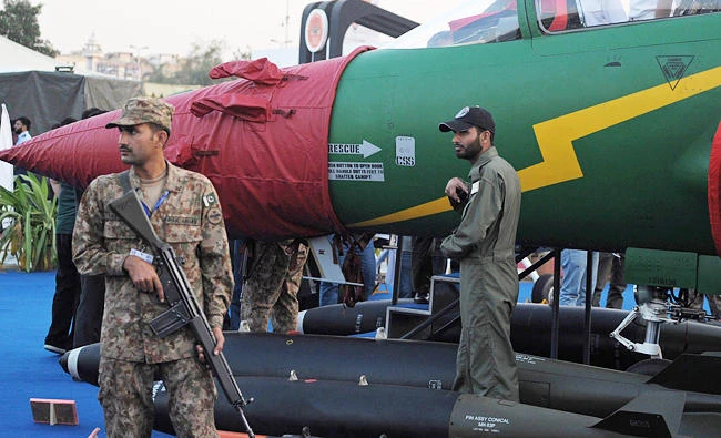 To go with Pakistan-military-defence-exports,FOCUS by Nasir JAFFRYA Pakistani soldier (L) keeps watch as a PAC JF-17 Thunder multirole combat aircraft, conceived and initially developed with the help of China, is pictured on static display at the International Defence Exhibition and seminar (IDEAS) in Karachi on December 3, 2014. A revamped version of Pakistan's JF-17 jet fighter took centre stage at a defence exhibition in Karachi this week as the restive nuclear-armed state looks to boost its role as a military exporter on the world stage. AFP PHOTO/Rizwan TABASSUM