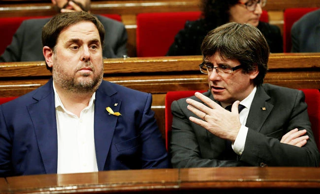 Catalan President Carles Puigdemont (R) talks to Catalan Vice President Oriol Junqueras at the start of a session at the Catalan regional Parliament in Barcelona, Spain, in this October 26, 2017 photo. (REUTERS)