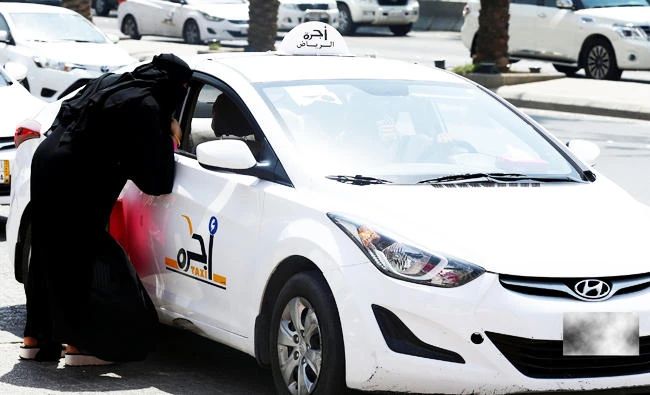 A Saudi woman speaks with a taxi driver to get a ride in Riyadh, Saudi Arabia September 28, 2017. REUTERS/Faisal Al Nasser