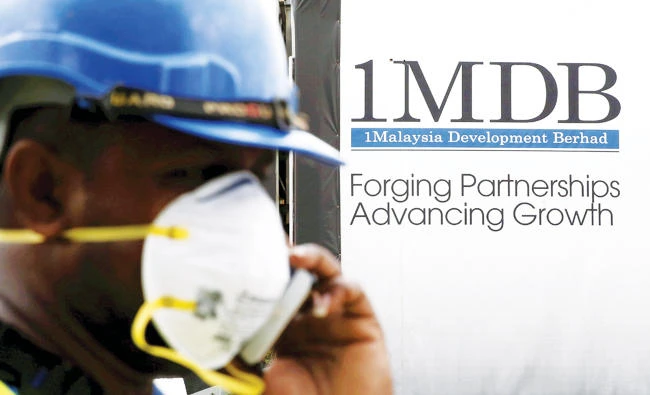 A construction worker talks on the phone in front of a 1Malaysia Development Berhad (1MDB) billboard at the Tun Razak Exchange development in Kuala Lumpur, Malaysia. (REUTERS)