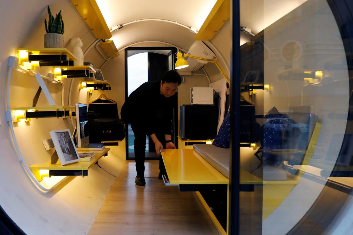 Architect James Law lays out a bed inside of his work, a 120-square-foot giant water pipe designed as micro-housing in Hong Kong. (Reuters)