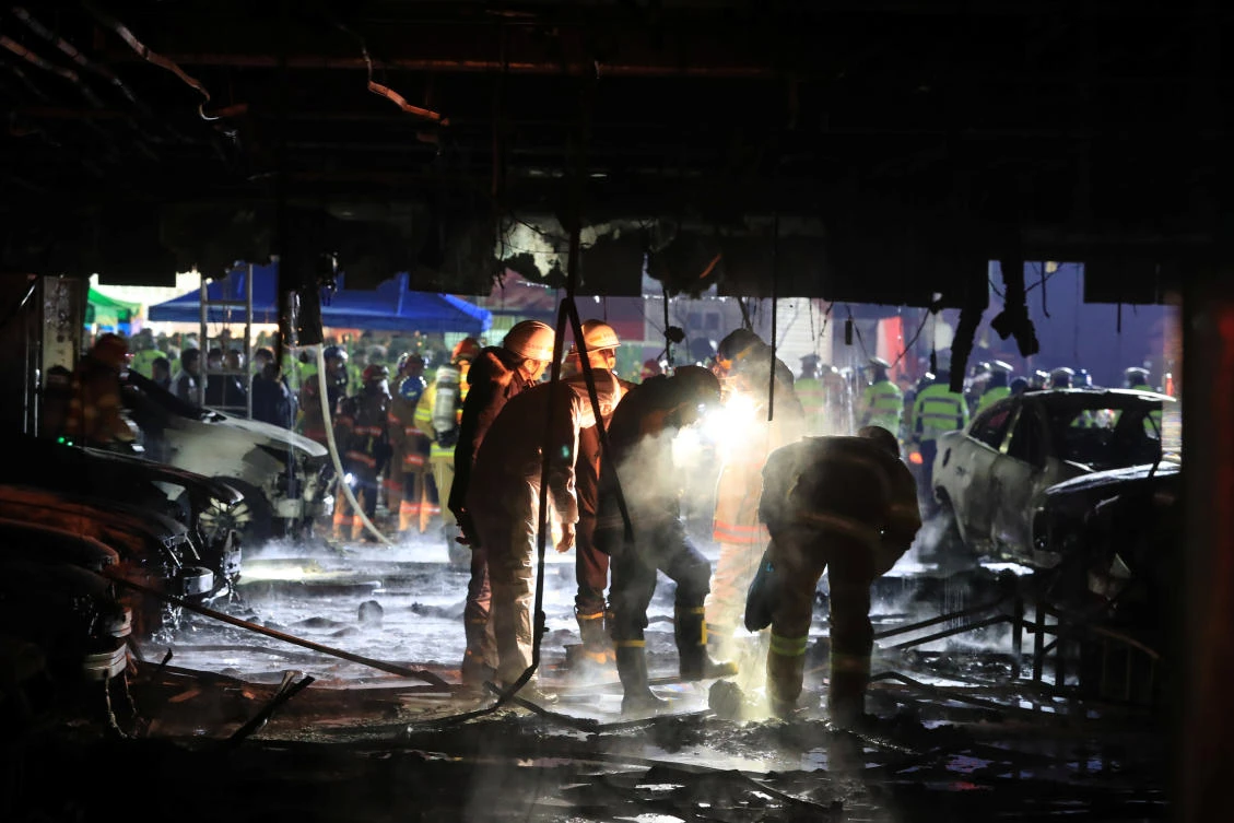 Firefighters examine an eight-story burned building in Jecheon, South Korea (Reuters)