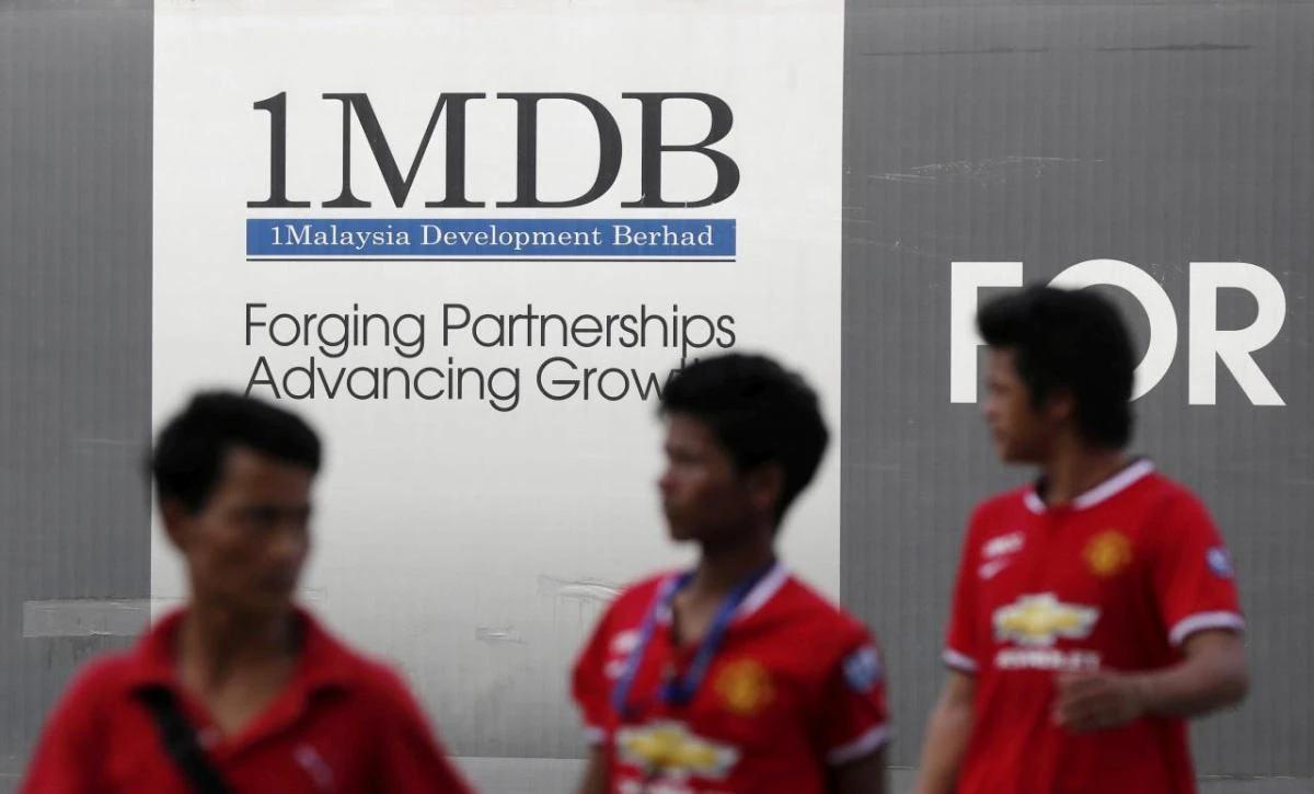 Men walk past a 1MDB billboard at the fund’s flagship Tun Razak Exchange development in Kuala Lumpur. The Malaysian company is the focus of money-laundering investigations in at least six countries. (Reuters)