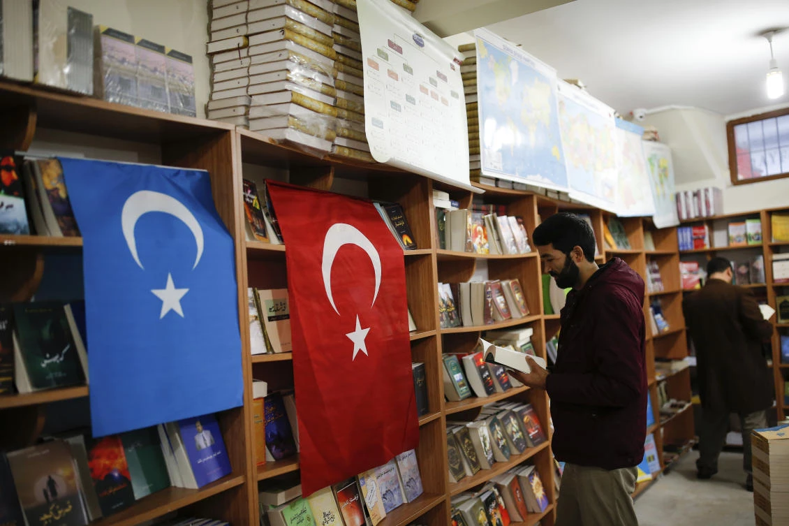 A man reads a book in a bookstore where flags which represents Turkey and ‘East Turkistan,’ the name Uighurs who oppose Chinese rule call their homeland, are hung in Istanbul’s Zeytinburnu neighborhood. (AP)