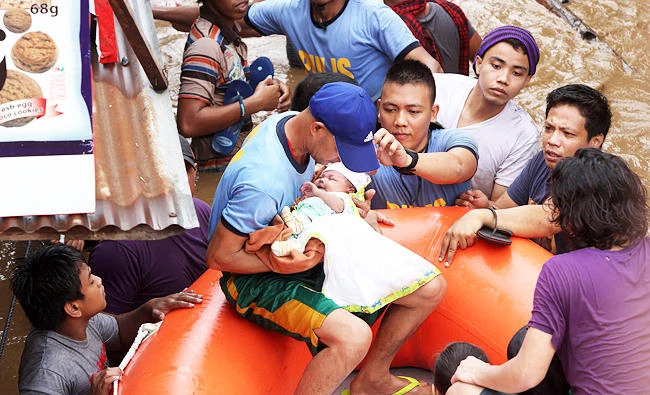 Policemen ecavuate a baby in Cagayan City on Friday, after the Cagayan River swelled caused by heavy rains brought by Tropical Storm Tembin. (AFP)