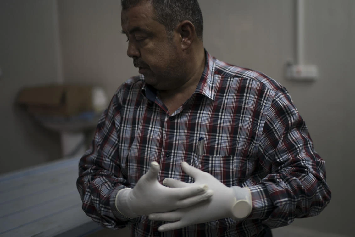 Chief medical assistant Raid Jassim adjusts his gloves before inspecting a body in a morgue in Mosul, Iraq. The morgue staff saw the worst of what the Daesh group was capable of inflicting on a human being. (AP)