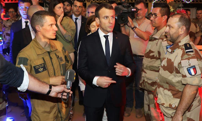 French president Emmanuel Macron, center, speaks to media during a Christmas diner with 700 French soldiers of Barkhane forces on Friday at the French air force base in Niamey. (AFP)