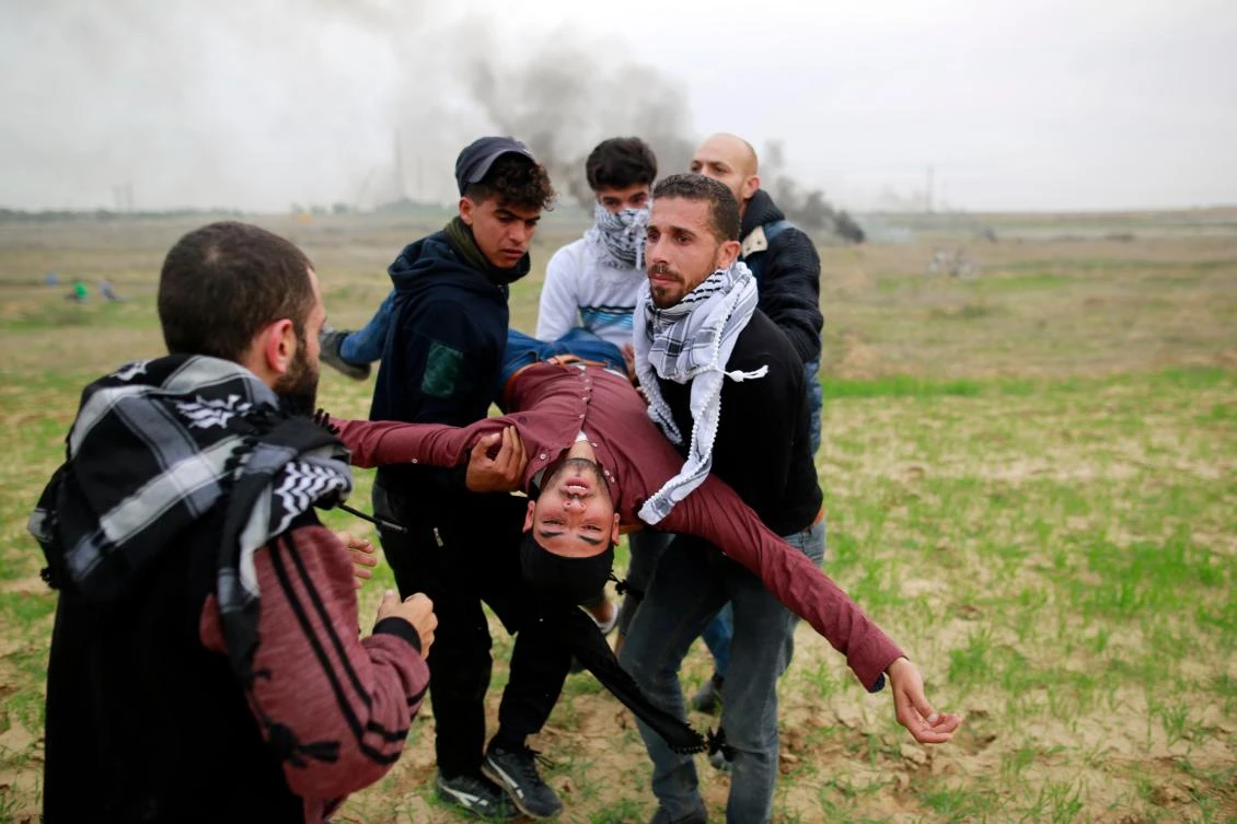 Above, Palestinian protesters carry a wounded comrade during clashes with Israeli soldiers near the border fence east of Gaza City on Friday, December 22. (AFP)