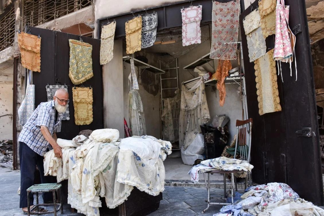 Delicately embroidered shawls and bright tarps are on display in Shawash's partly restored storefront, the only colours visible in a sea of smashed concrete and debris-laden roads. (AFP)