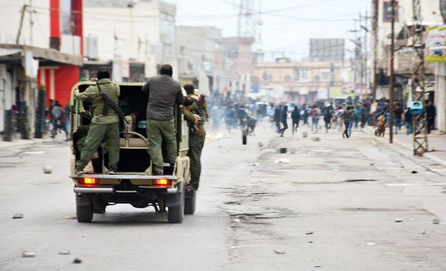A photo taken on December 20, 2017 shows security forces riding in a vehicle as they chase down demonstrators in a street in the city of Raniya, 130 kilometres north of Sulaymaniyah in the autonomous Iraqi Kurdistan region. (AFP)