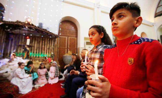 Iraqi Christians children carry candles during a mass on Christmas eve at St.George Chaldean Church in Baghdad, Iraq on Sunday. (REUTERS)