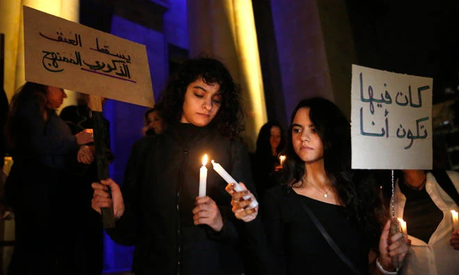 Lebanese women hold candles and placards that read in Arabic: "Down with organized male violence", left, and "It could have been me", right, during a vigil sit-in to protest violence against women, outside the national museum, in Beirut, Lebanon, on Dec. 23, 2017. (AP)