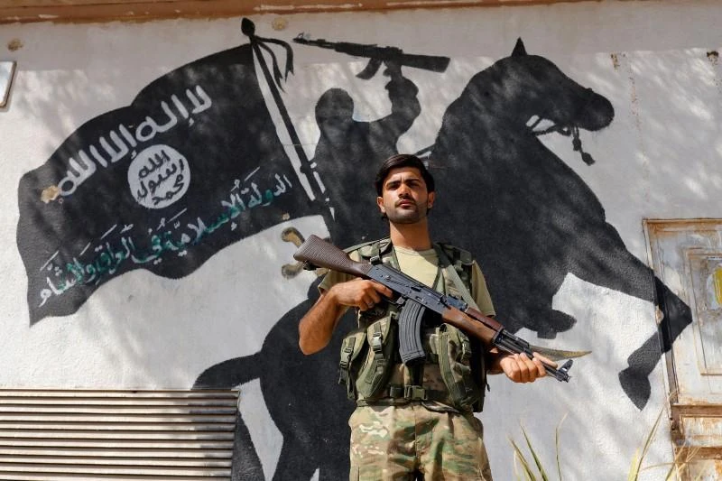 Above, a member of the Turkish-backed Free Syrian Army stands in front of a Daesh mural in the border town of Jarablus, Syria. President Bashar Assad’s main ally Russia also said on Wednesday the main battle with Daesh in Syria was over. (Reuters)