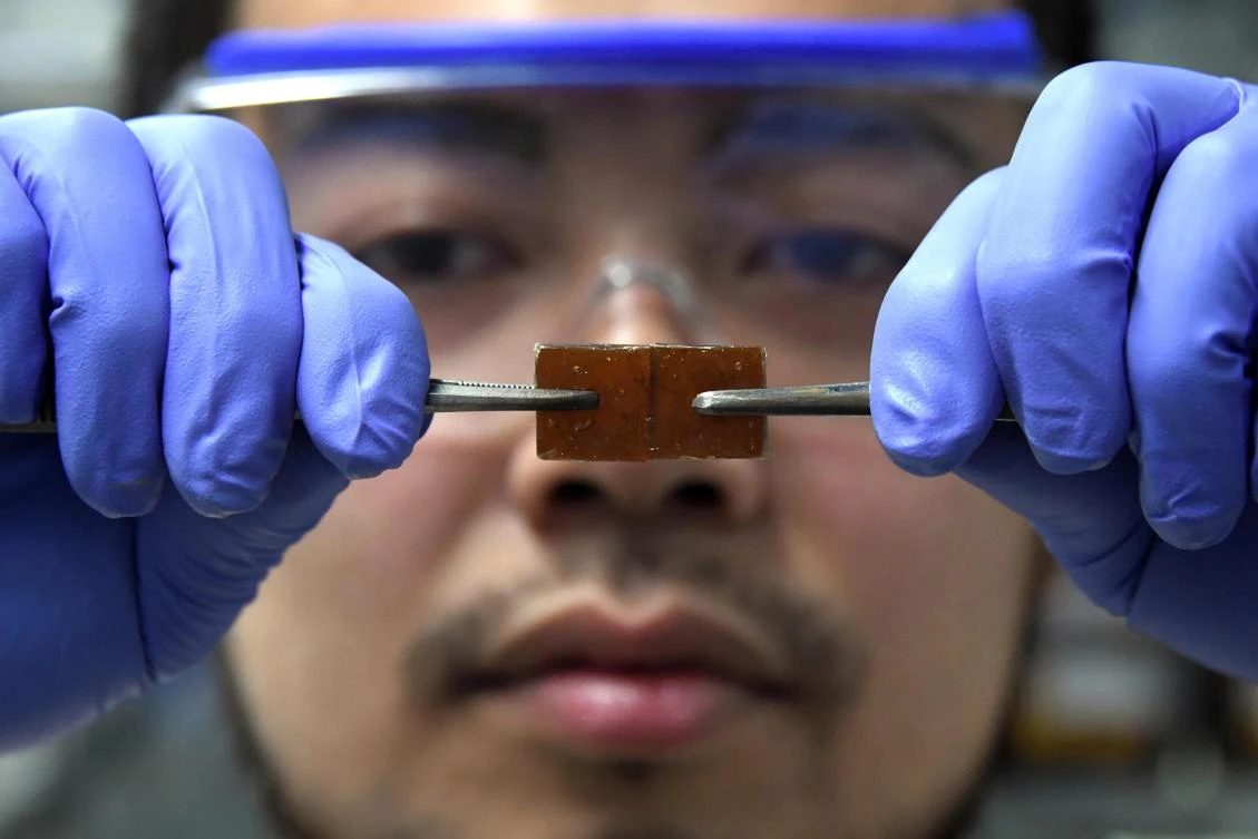 In this picture taken on December 25, 2017, Yu Yanagisawa, a chemistry researcher at the University of Tokyo, presses together two pieces of resin glass together to repair them at the university's lab in Tokyo. The Japanese researcher has developped -- by accident-- a new type of glass that can be repaired simply by pressing it back together after it has cracked. (AFP)