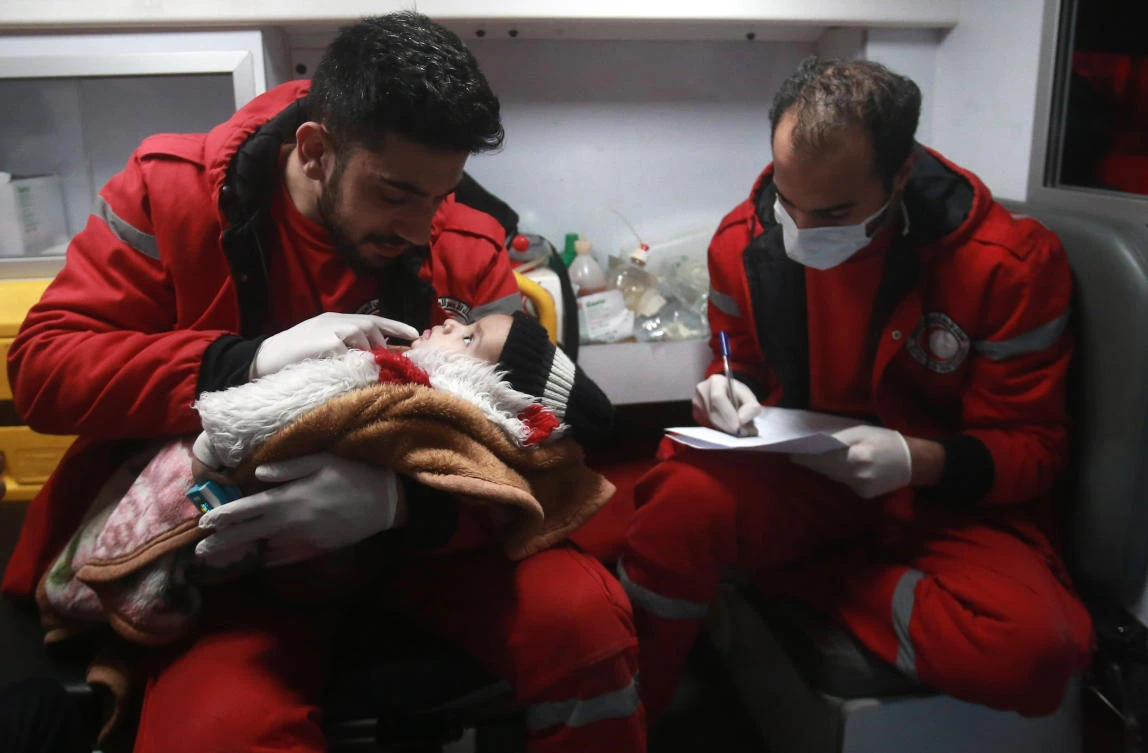 Paramedics tend to a baby inside an ambulance on the second night of an evacuation operation, led by the Syrian Red Crescent and the International Committee of the Red Cross, in Douma on the edge of Damascus. (AFP)