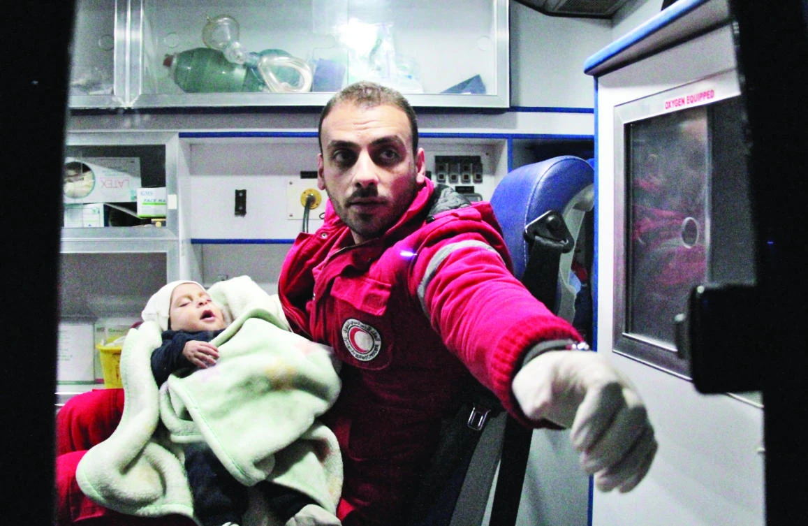 A paramedic holds a baby inside an ambulance during an evacuation operation on Wednesday in Eastern Ghouta, Syria. (AFP)