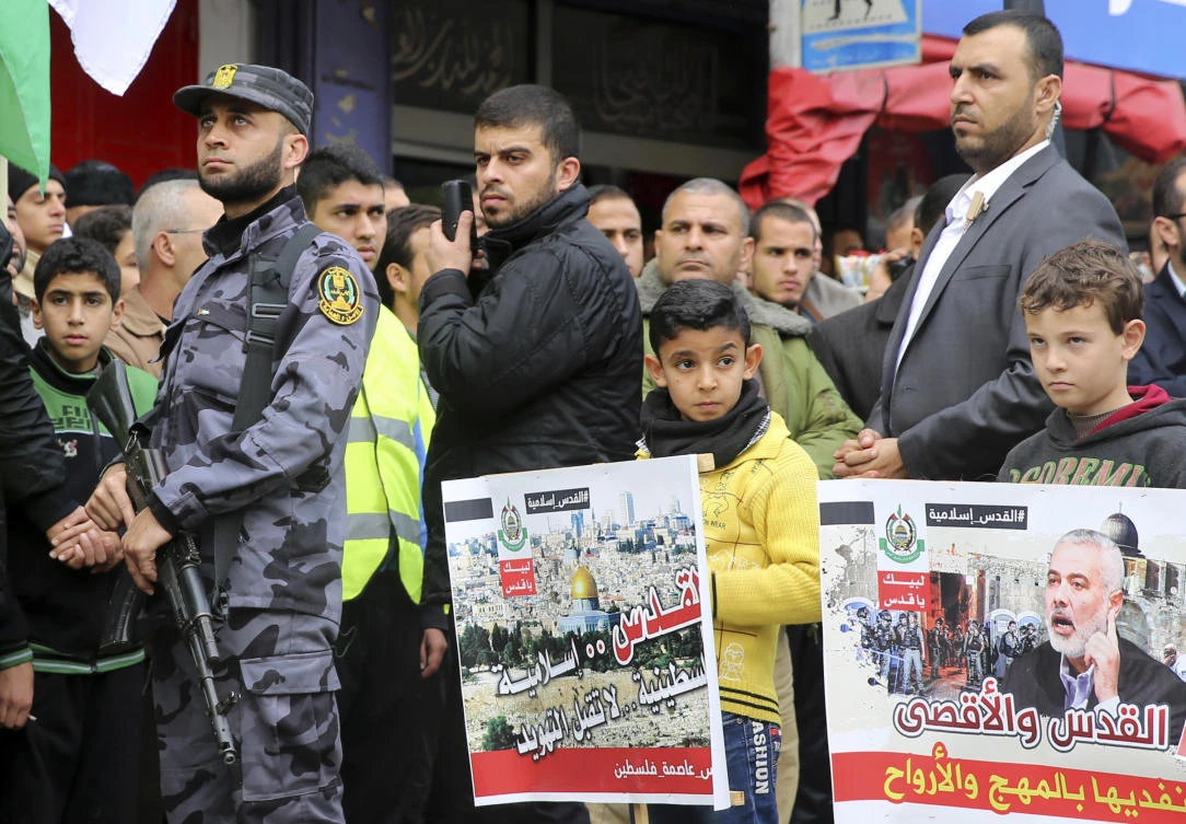 Children hold posters near Hamas security officers during a protest against US President Donald Trump’s decision to recognize Jerusalem as Israel’s capital, in Gaza City, Friday, Dec. 29, 2017. (AP)