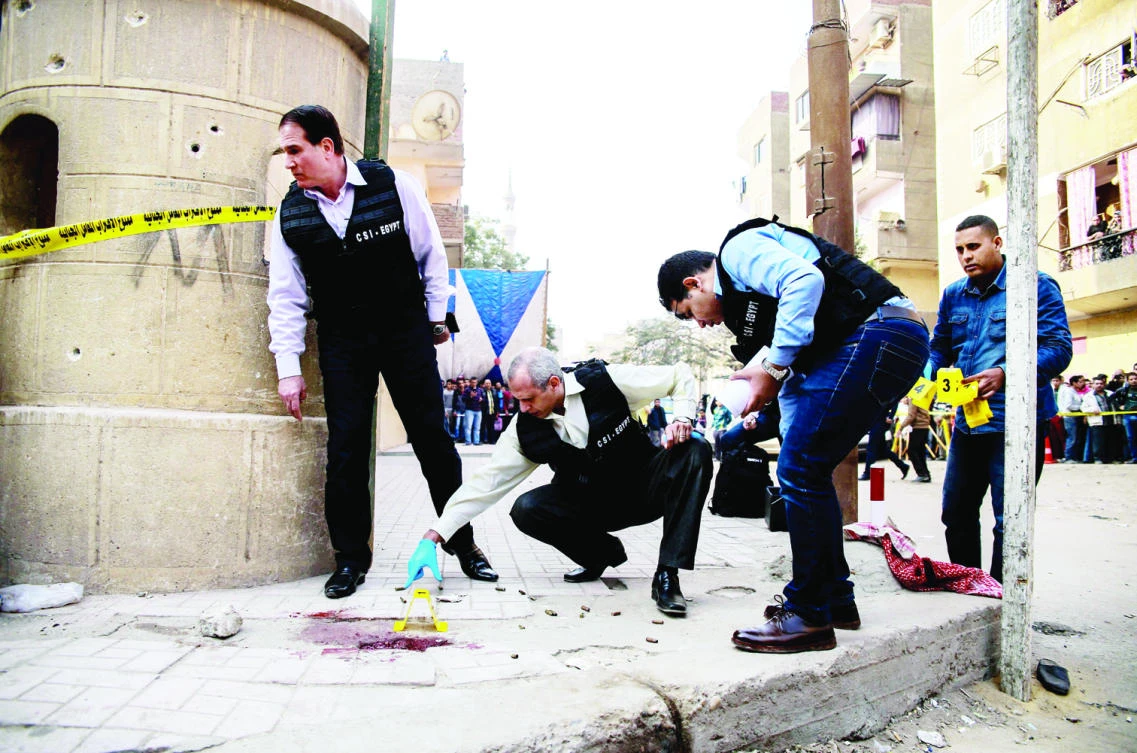 Security personnel and forensic experts inspect the site of an attack outside a church, south of Cairo, on Friday. (AFP)