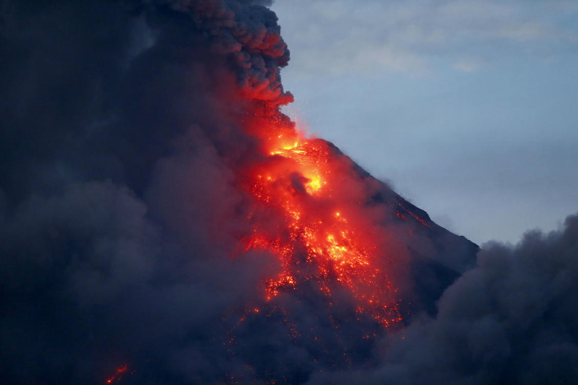 Mayon volcano spews red -hot lava in another eruption as seen from Legazpi city, Albay province, roughly 200 miles (340 kilometers) southeast of Manila, Philippines, Tuesday, Jan. 23, 2018. Mayon has spewed fountains of red-hot lava and massive ash plumes anew in a dazzling but increasingly dangerous eruption that has sent 56,000 villagers fleeing to evacuation centers. (AP Photo/Bullit Marquez)