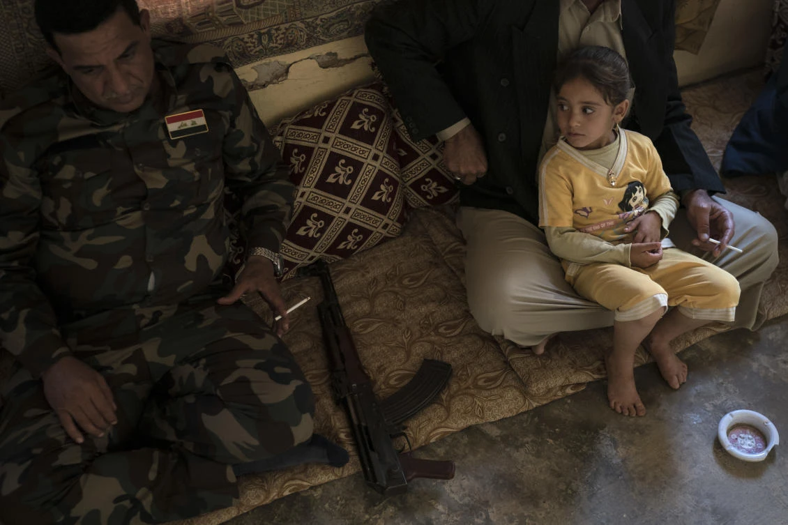 In this Nov. 12, 2017 photo, a local fighter and residents gather at the mayor’s home in the Bijwaniya village, south of Mosul, Iraq. Five young men were taken by unidentified gunmen after the village was liberated from Daesh militants and despite months of searching; their families haven’t been able to locate them. (AP/Felipe Dana)