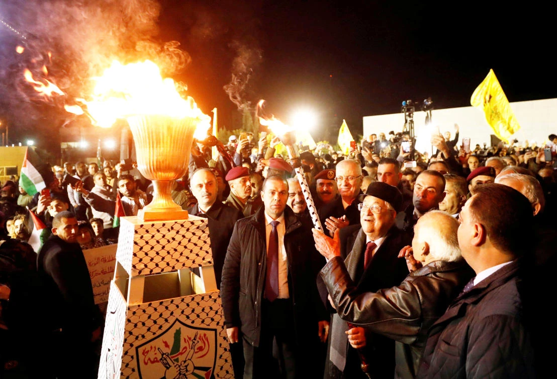 Palestinian President Mahmoud Abbas lights a torch during Sunday’s rally in Ramallah, marking the 53rd anniversary of the founding of the Fatah movement. (Reuters)
