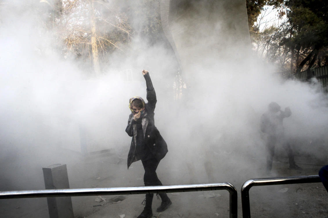 In this Saturday, Dec. 30, 2017 file photo a university student attends a protest inside Tehran University while a smoke grenade is thrown by anti-riot Iranian police, in Tehran, Iran. (AP)