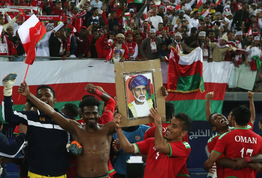 Oman's players hold a picture of Oman's Sultan as they celebrate with their fans after winning the semi-final match against Bahrain. (AFP)
