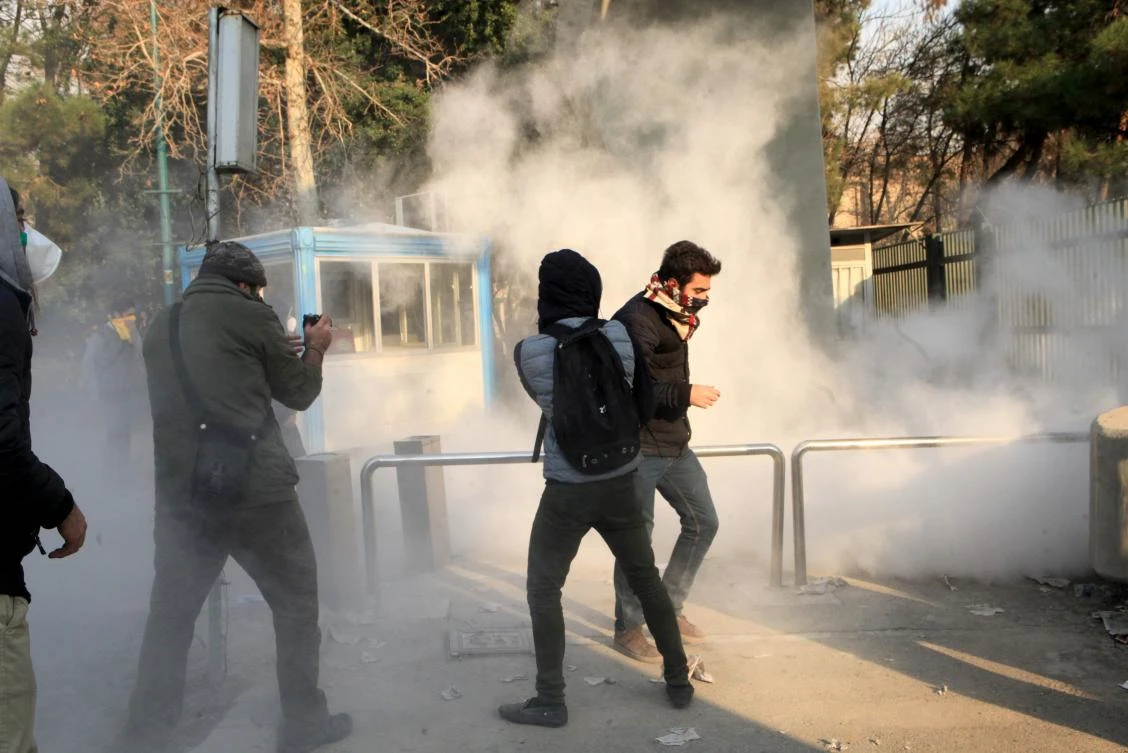 Iranian students run for cover from tear gas at the University of Tehran during a demonstration. (AFP)