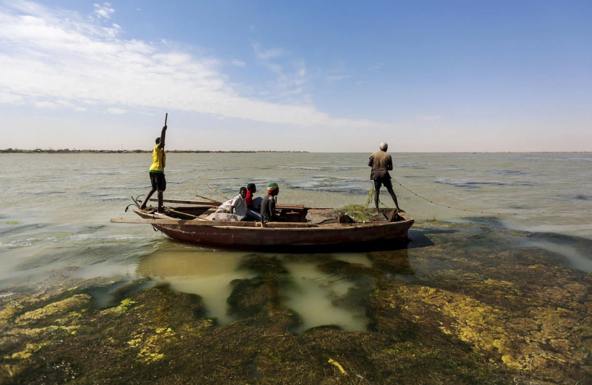Sudanese fishermen sail through river algae while fishing on the Nile River on the outskirts of Khartoum, Sudan. (AP)