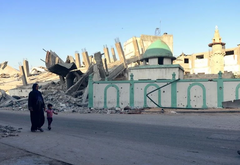A Palestinian woman and a child walk past the destroyed Omari mosque on August 12, 2014 in Jabaliya, northern Gaza Strip. (AFP)