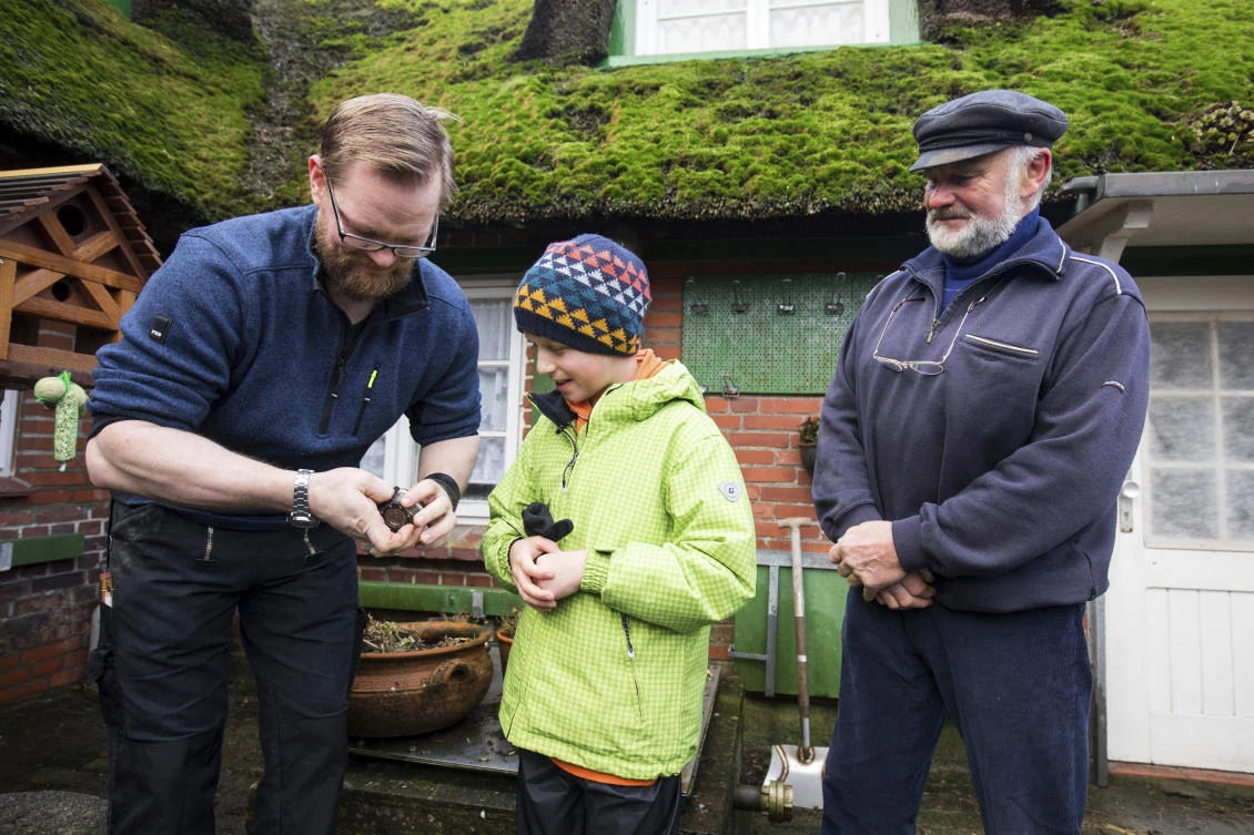 Island residents Holger Spreer, left, his father Roland Spreer, right, hand over a little camera to William Etherton on the island of Suederoog, Germany Saturday, Jan. 6, 2018. The English boy has been reunited in Germany with a video camera he lost four months ago on the other side of the North Sea.(AP)