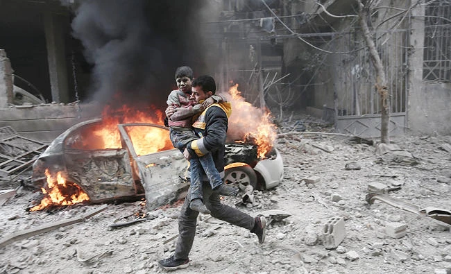 A Syrian paramedic carries an injured child following airstrikes by Syrian and Russian forces in the opposition-held town of Hamouria, Eastern Ghouta, on Saturday. (AFP)