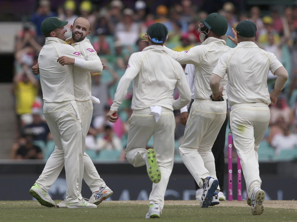 Australia's Nathan Lyon, second left, is congratulated by Shaun Marsh, left, after bowling England's Alastair Cook for 10 runs during the fourth day of their Ashes Test match in Sydney. (AP)