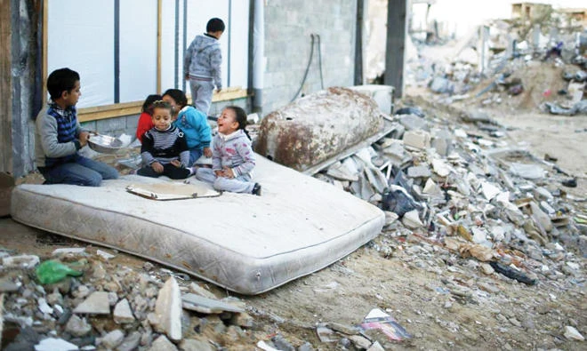 Palestinian children play on a mattress near the ruins of houses which witnesses said were destroyed by Israeli shelling in Gaza in 2014. (Reuters)