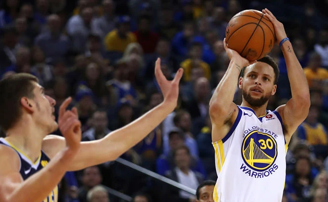 Golden State Warriors’ Stephen Curry, right, shoots against Denver Nuggets’ Nikola Jokic during their NBA game on Monday, January 8. (AP)