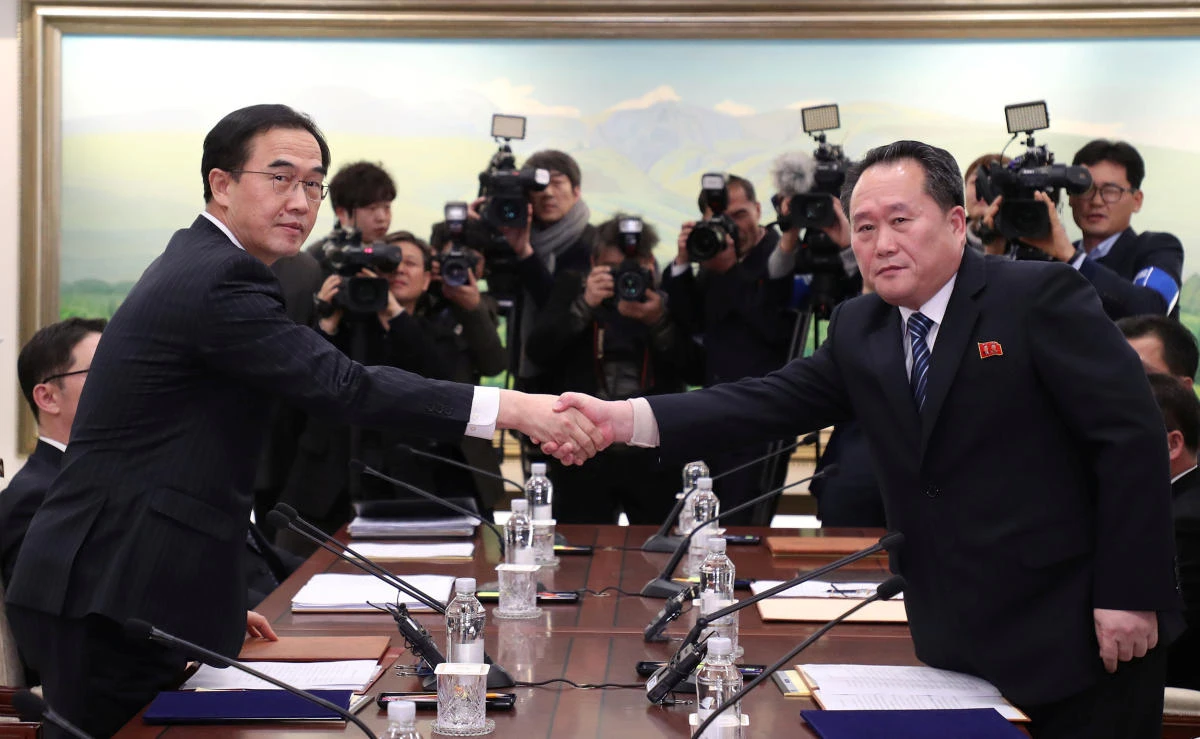 Head of the North Korean delegation, Ri Son Gwon shakes hands with South Korean counterpart Cho Myoung-gyon as they exchange documents after their meeting at the truce village of Panmunjom in the demilitarised zone separating the two Koreas, South Korea, Jan. 9, 2018. (Yonhap via Reuters)