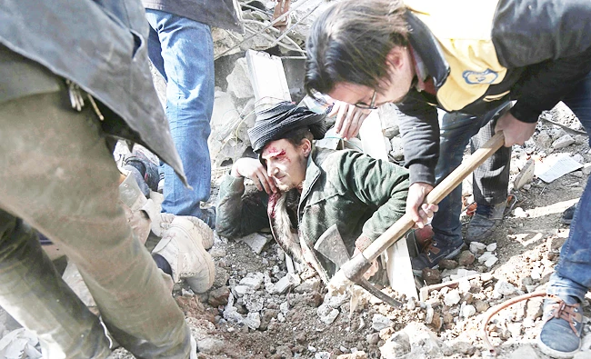 Volunteers from the White Helmets dig a man out of the rubble following an air strike on Saqba, in the besieged rebel-held Eastern Ghouta area near Damascus, on Tuesday. (AFP)