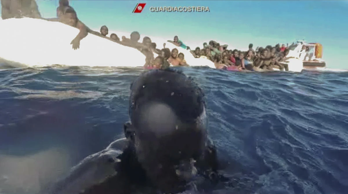 A frame grab from an Italian Coast Guard video on January 6 in the Mediterranean Sea off Libya shows migrants being rescued from dinghies as they try to cross to Italy. (Italian Coast Guard via AP)