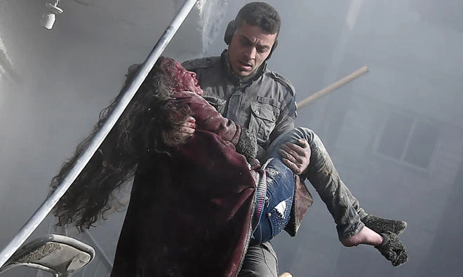 A volunteer from the Syrian civil defense group White Helmets carries a wounded girl after digging her out of the rubble following an airstrike on Hammuriyeh, in Eastern Ghouta , on Tuesday. (AFP)
