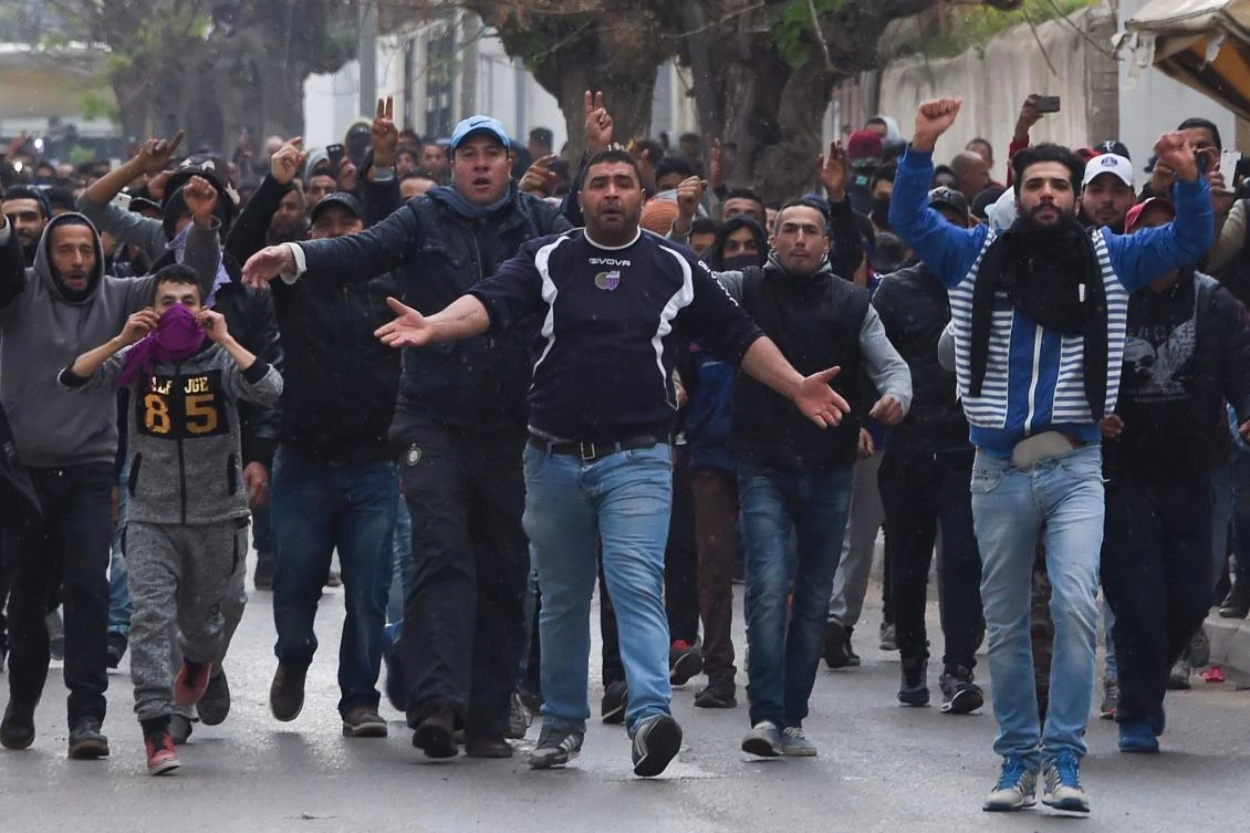 Tunisian protesters gesture toward security forces during clashes in the town of Tebourba on January 9, 2018, following the funeral of a man who was killed the previous day in a demonstration over rising costs and government austerity. (AFP)