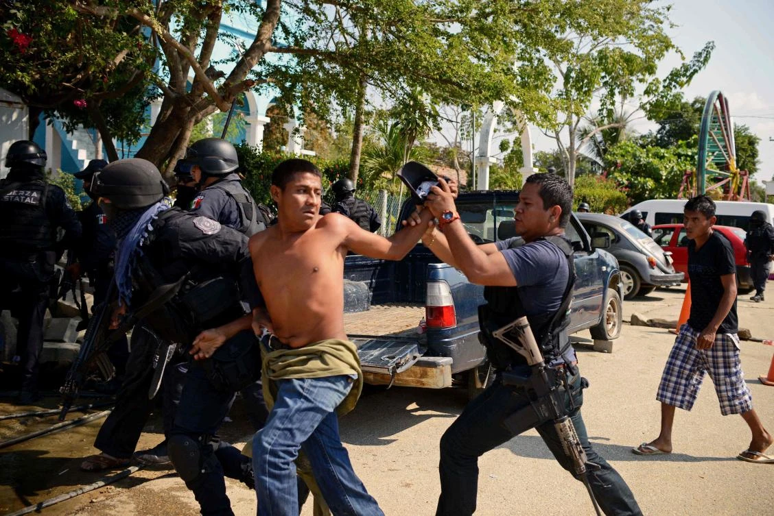 A member of the Regional Coordinator of Community Authorities (CRAC) is arrested by Guerrero state policemen after a series of clashes that has left at least 11 people dead at La Concepcion village, Acapulco municipality, in Guerrero state, Mexico, on Jan. 7, 2018. At least 11 people were killed and 30 arrested during armed clashes among civilians, community guards and police in a rural area of Acapulco, in southern Mexico, the Guerrero government confirmed. (AFP/Francisco Robles)