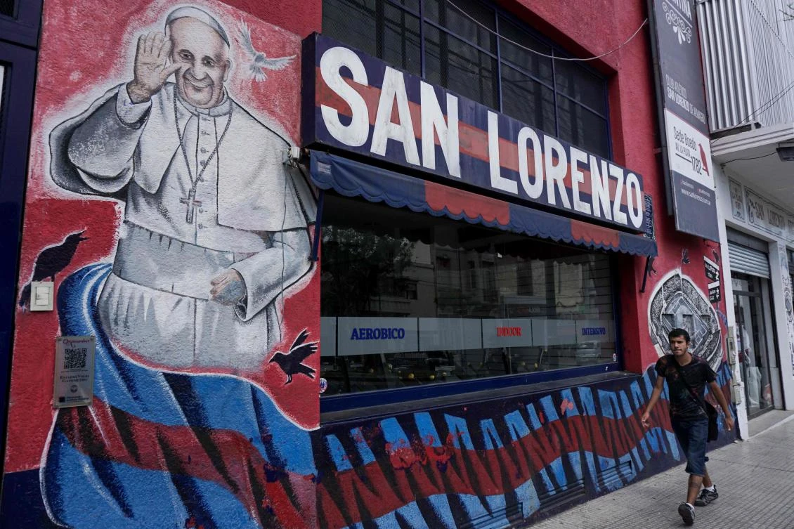A man walks past a store of Argentine San Lorenzo de Almagro sports club decorated with a graffiti depicting Pope Francis in Buenos Aires on Jan. 03, 2017. Pope Francis returns to Latin America for the sixth time in his pontificate on January 15, 2018 avoiding again his native Argentina, a significant gesture that brings up many questions. (AFP/Eitan Abramovich)